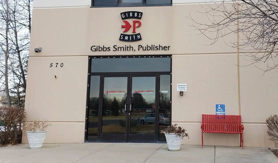 The exterior of a beige building with a glass entrance and prominent signage for ’Gibbs Smith, Publisher.’