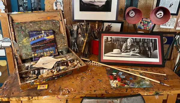 An open, well-used wooden artist’s box filled with tubes of paint and brushes.