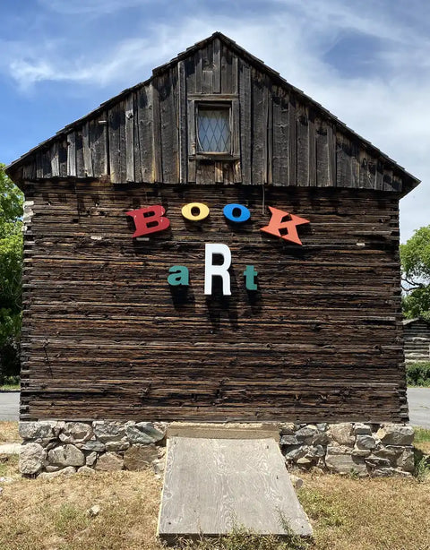 Weathered wooden building with colorful letters spelling ’BOOK art’.