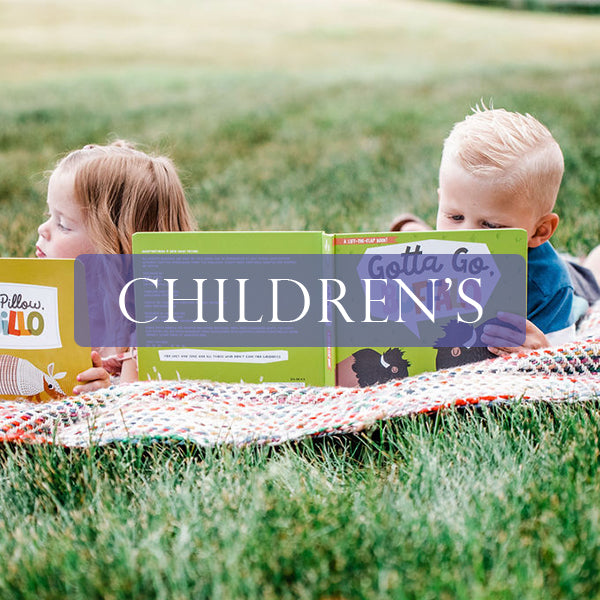 Two children relaxing in a grassy field reading Gibbs Smith childrens' books.
