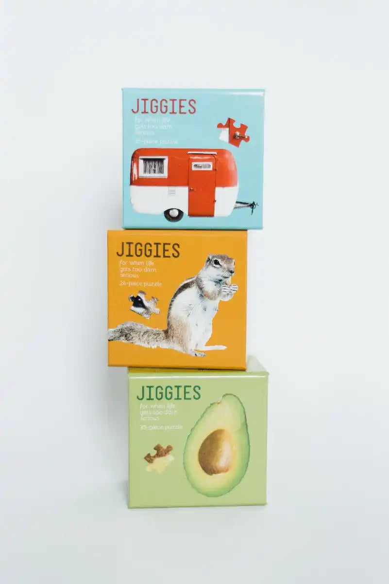 Three stacked jigsaw puzzle boxes with different designs.